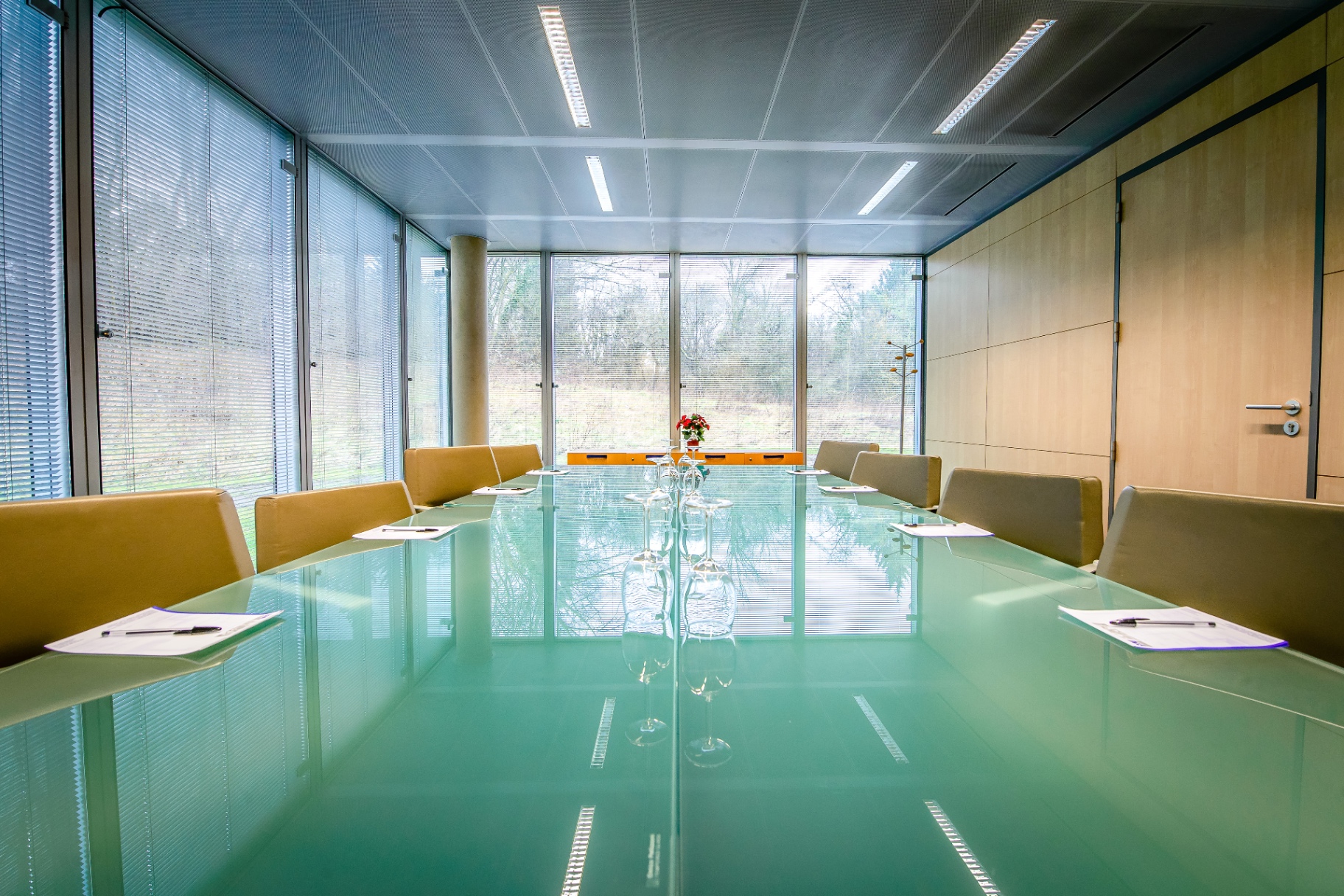Salle de réunion lumineuse, table en verre, baies vitrées sur la nature