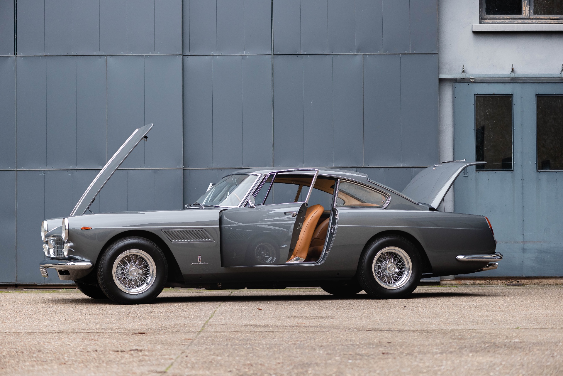 Ferrari 250 GT Coupé grise, profil, capots et portes ouverts devant un hangar